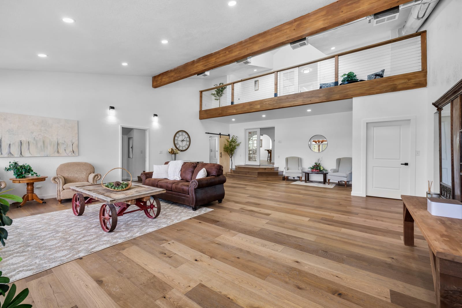 Bright open common living area with wood floors, exposed beams, and comfortable seating at the New Frontier Recovery Center property in Huntley, Montana