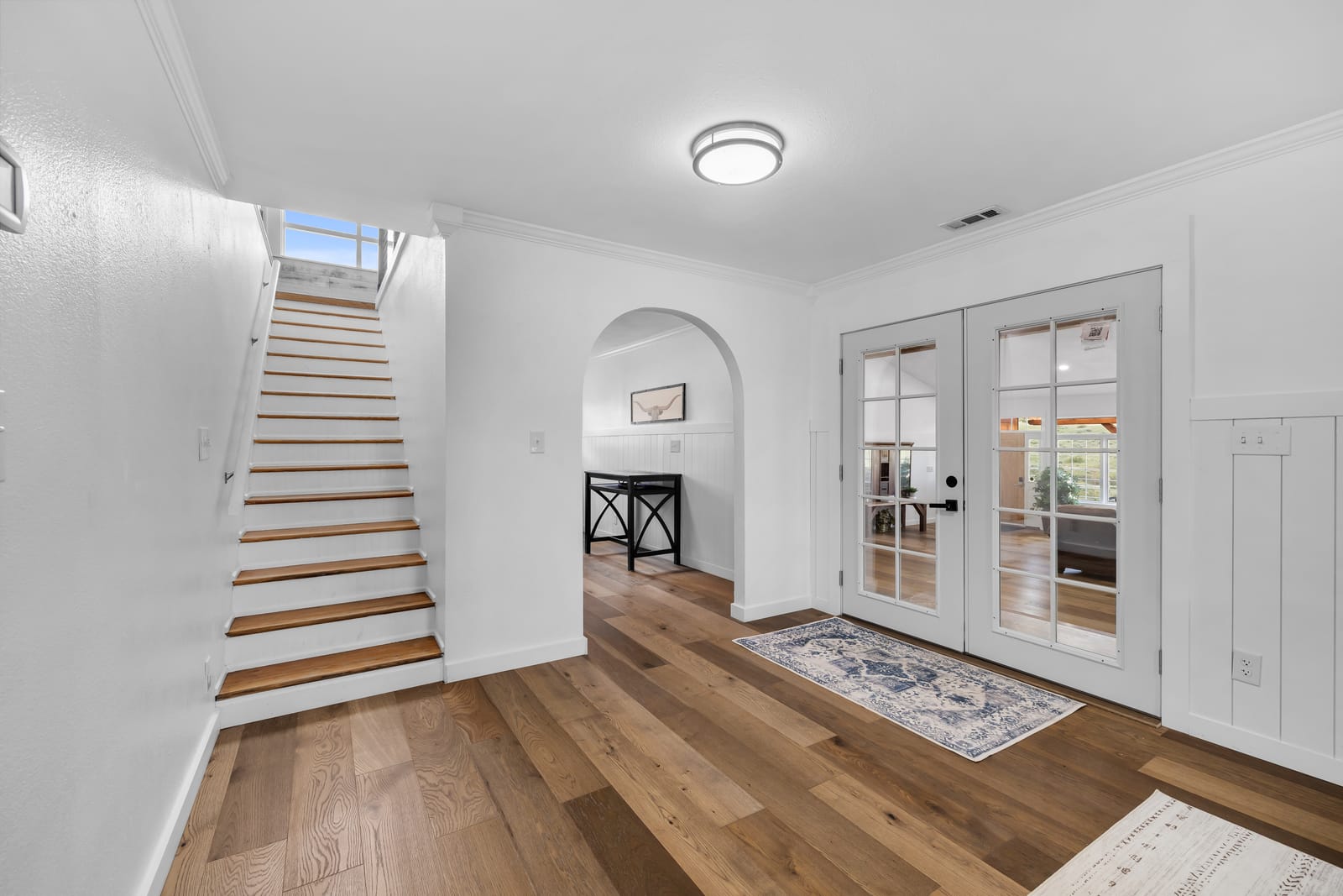 Welcoming entry foyer with a wood staircase and French doors at New Frontier Recovery Center in Huntley, Montana